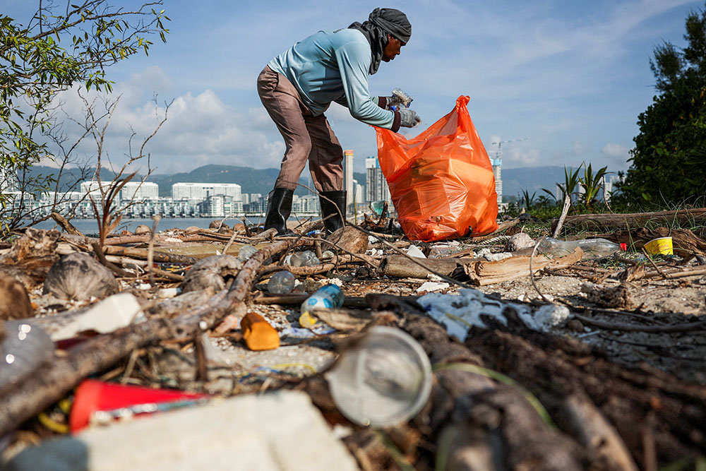 A volunteer collects rubbish during a beach cleanup campaign organized in conjunction with the Earth Day celebration in George Town, Malaysia, April 22, 2024. (OSV News/Reuters/Hasnoor Hussain)