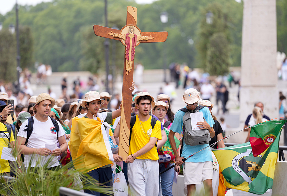 Young pilgrims carry a cross as they walk toward the Vatican during a pilgrimage in Rome, July 28, 2025. (CNS/Lola Gomez)