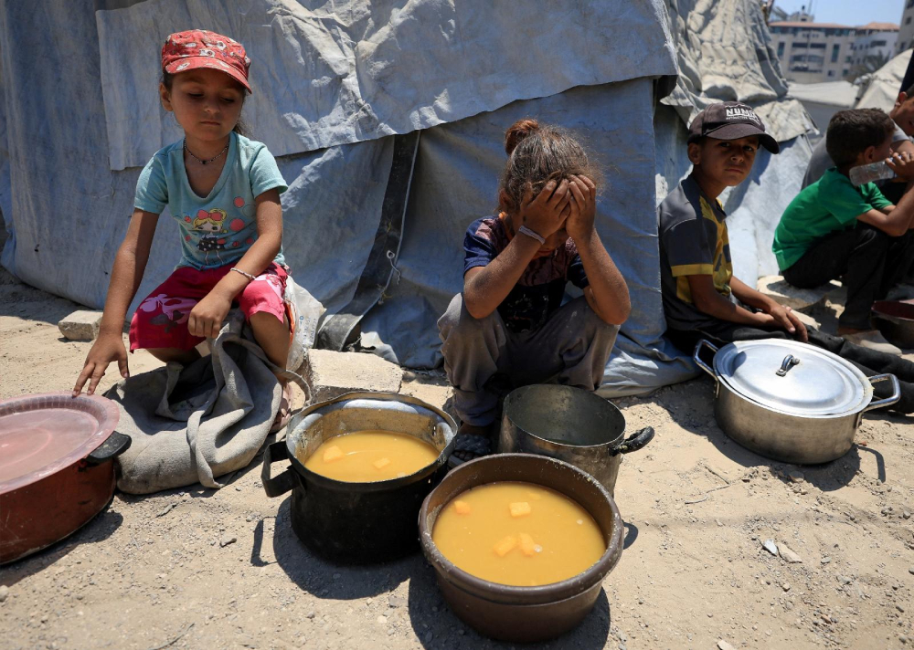 Palestinian children react near pots of food from a charity kitchen in Gaza City July 25, 2025, amid a hunger crisis. For months, U.N. officials, aid groups and experts have warned that Palestinians in the Gaza Strip are on the brink of famine without formally declaring one. (OSV News/Dawoud Abu Alkas/Reuters)