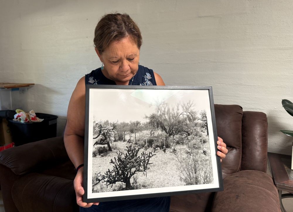 Dora Rodriguez looks at a black and white image of crosses in desert.