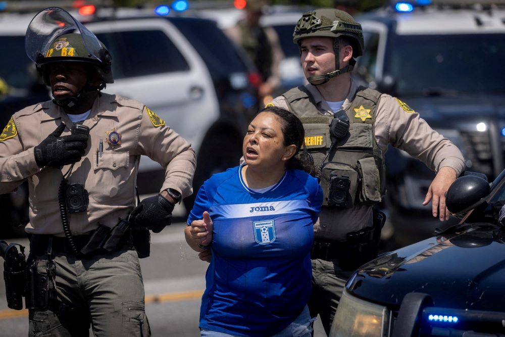 Los Angeles County Sheriff's deputies detain a woman during a standoff by protesters and law enforcement.