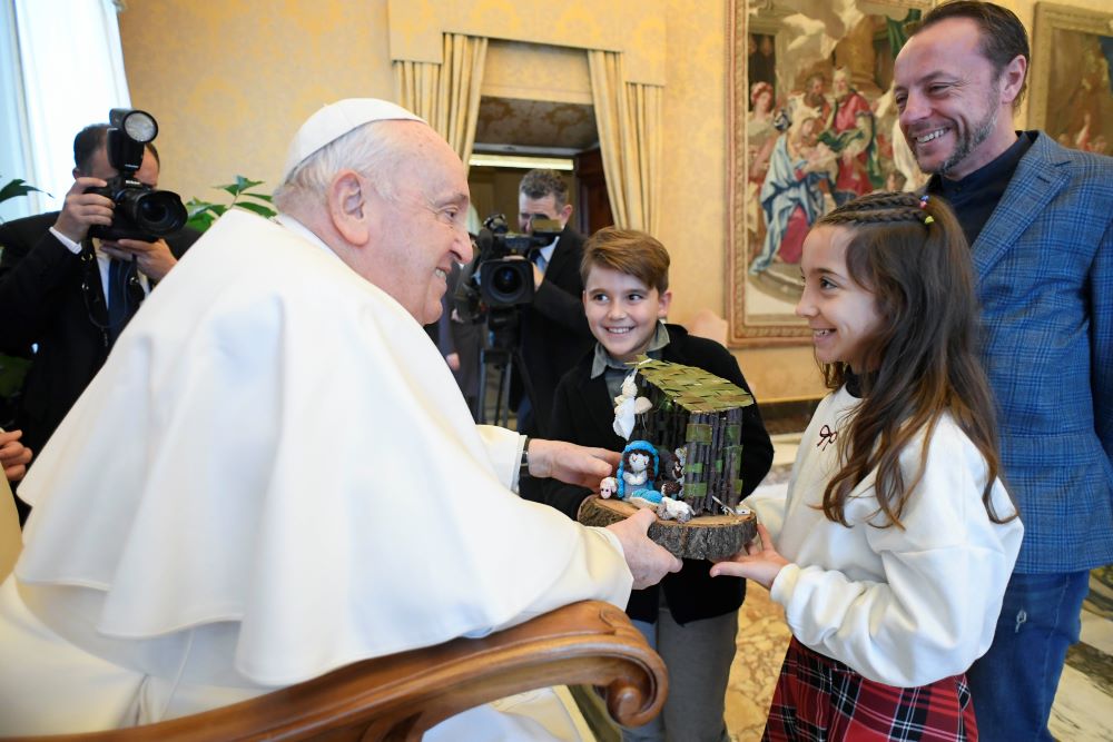 Pope Francis receives a small Nativity scene from a child.