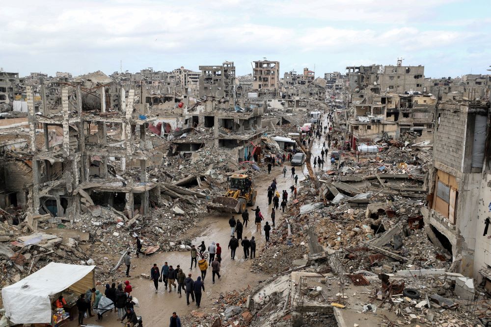 Palestinians walk past the rubble of destroyed buildings in Gaza City.