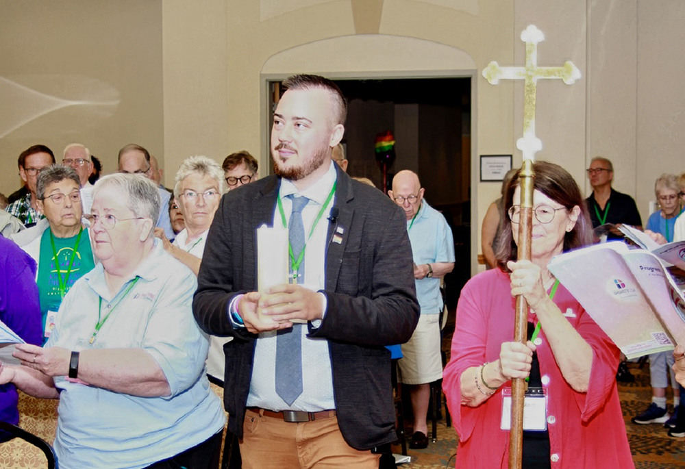 Max Kuzma carries a candle alongside Ann Penick during the liturgy procession on Sunday, July 6 on the final day of the Dignity USA conference. The title of the conference, focused on the inclusion of LGBTQ+ Catholics, was "We Are God’s People: Here, Now, Always." (Neal Raffensberger)