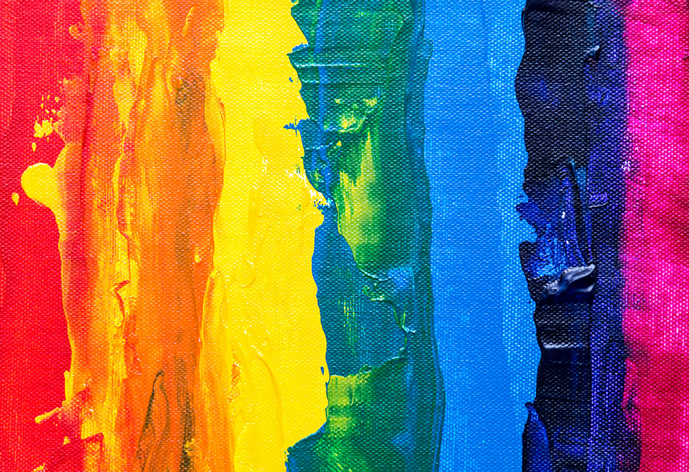 An abstract rainbow illustration shows a close-up photo of vertical paint brush strokes of the colors red, orange, yellow, green, blue, and purple (Unsplash/Steve Johnson)