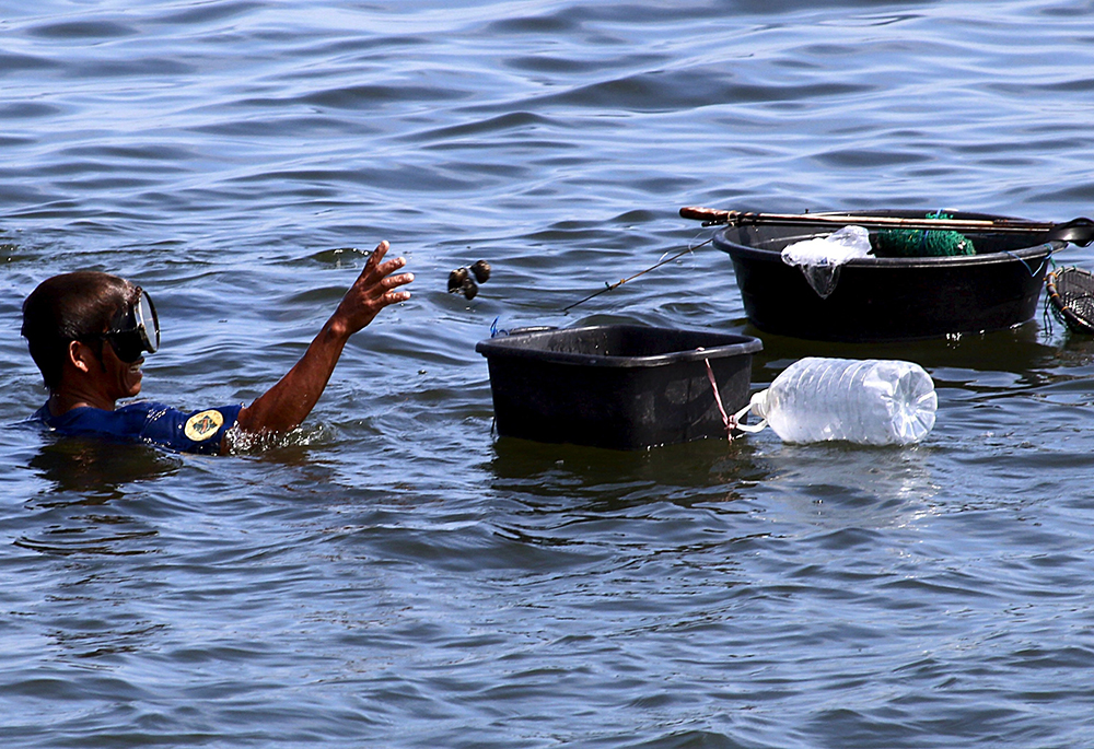 A fisherman collects sea shells in Manila Bay at Cavite City, near Manila, Philippines, July 23, 2015, the year of the publication of Pope Francis' encyclical "Laudato Si', on Care for Our Common Home." (CNS/Reuters/Romeo Ranoco)