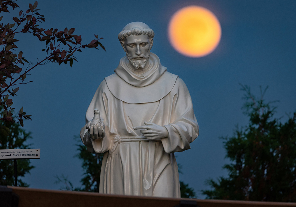 A hunter's moon rises behind a statue of St. Francis of Assisi on the grounds of the National Shrine of Our Lady of Champion in Champion, Wisconsin, Oct 8, 2022. (OSV News/CNSSam Lucero)