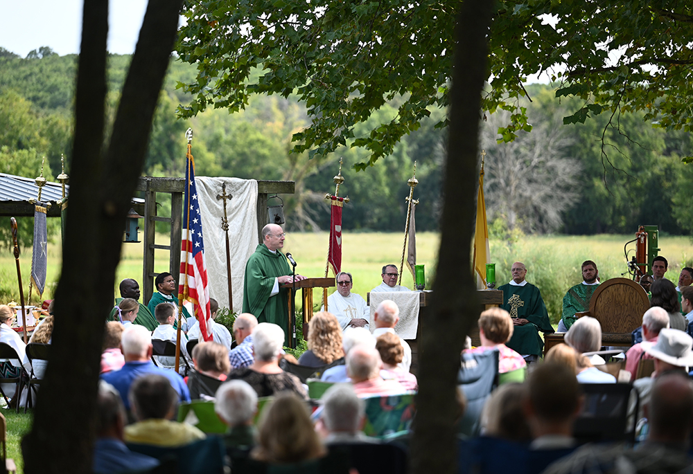 Then-Bishop Shawn McKnight of Jefferson City, Missouri, surrounded by eight concelebrating priests and about 350 people from parishes all over the diocese, preaches the homily during the diocese’s inaugural Rural Life Mass Sept. 8, 2024, on the Steinman family farm near Vienna. Congregants were seated on lawn chairs, blankets or hay bales under shade trees in the late-summer sun. (OSV News/The Catholic Missourian/Annie Williams)