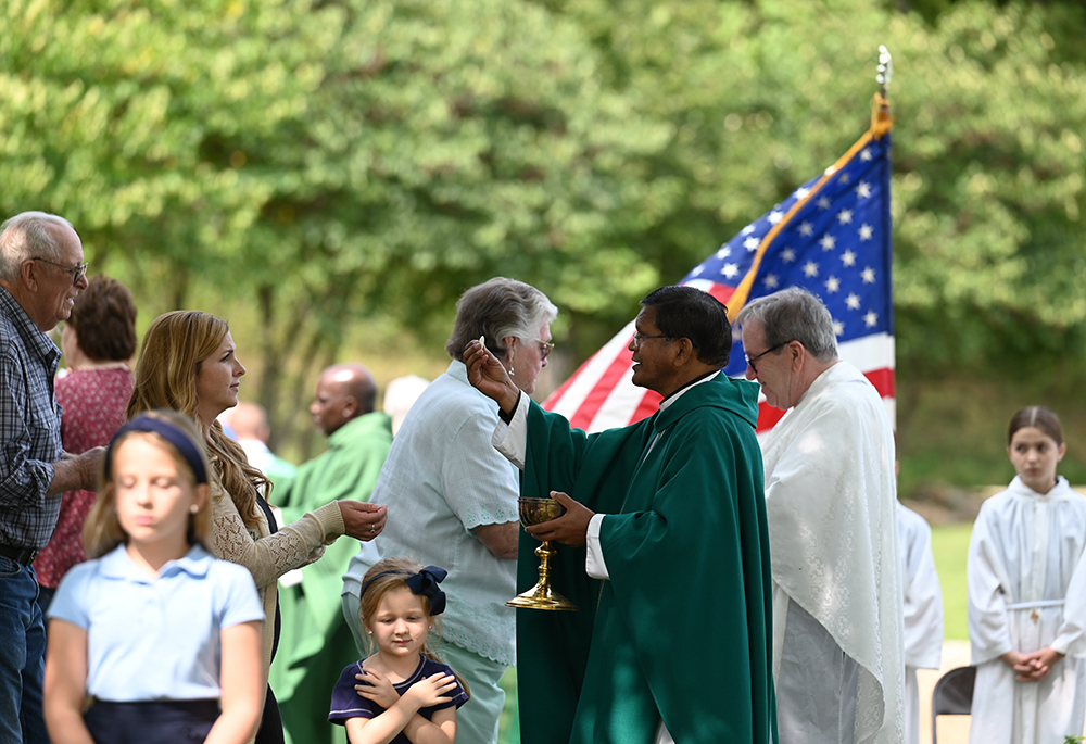 Fr. Basil Tigga and Fr. Matthew Flatley distribute Communion during the inaugural Rural Life Mass of the Diocese of Jefferson City, Missouri, on the Steinman family farm near Vienna Sept. 8, 2024. (OSV News/The Catholic Missourian/Annie Williams)