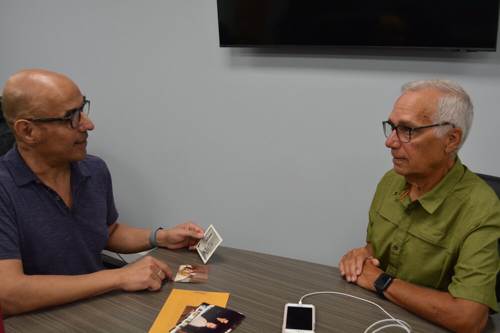 Pope Leo XIV's brother John Prevost, right, and his friend Augustinian Fr. Ray Flores, look at a photo of what Prevost guessed was the pope's ninth birthday cake and ice cream celebration. (OSV News/Simone Orendain)