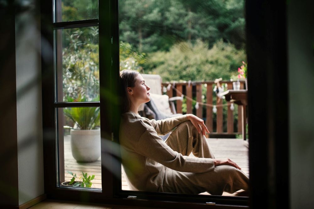 Woman sits by window.