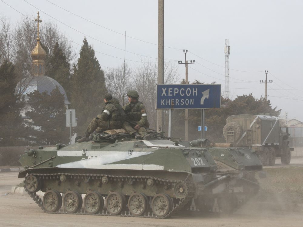 Servicemen ride past a church on a Russian army tank in Armyansk, Crimea, Feb. 24, 2022.
