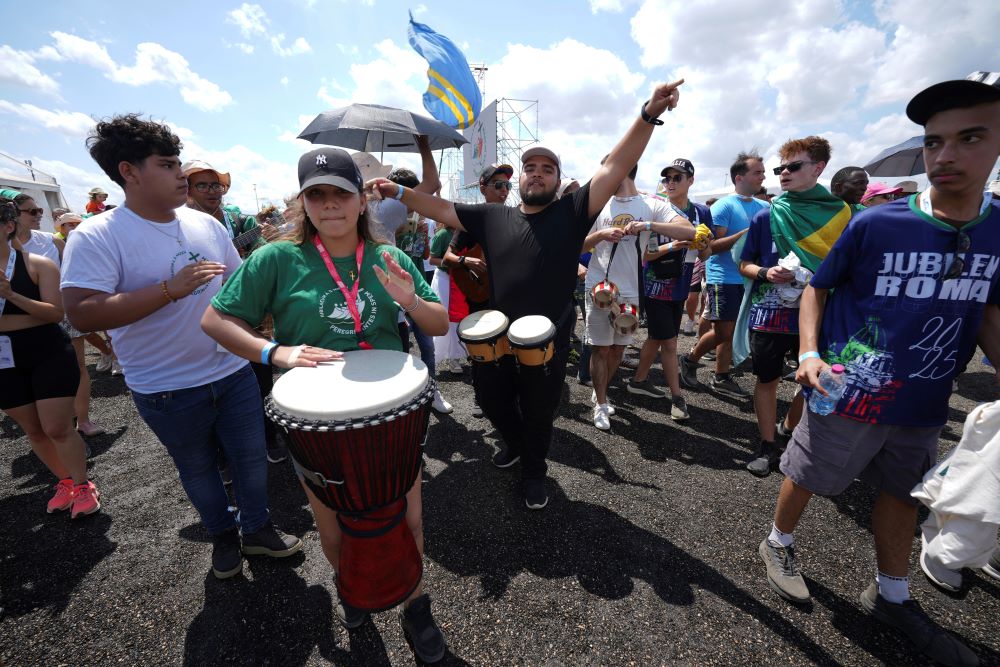 Crowd of young people walking, with person with drum in front