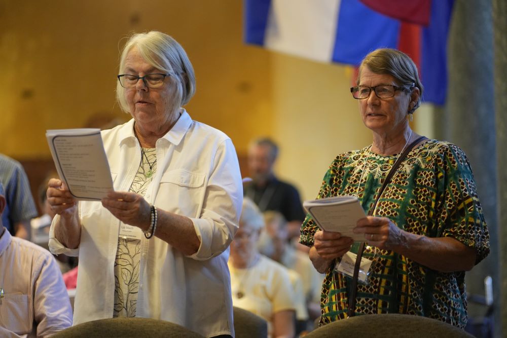 Liz Mach and Mary Orth-Lauer read from a booklet as they renew their commitment to living a life of mission during a Mass. 