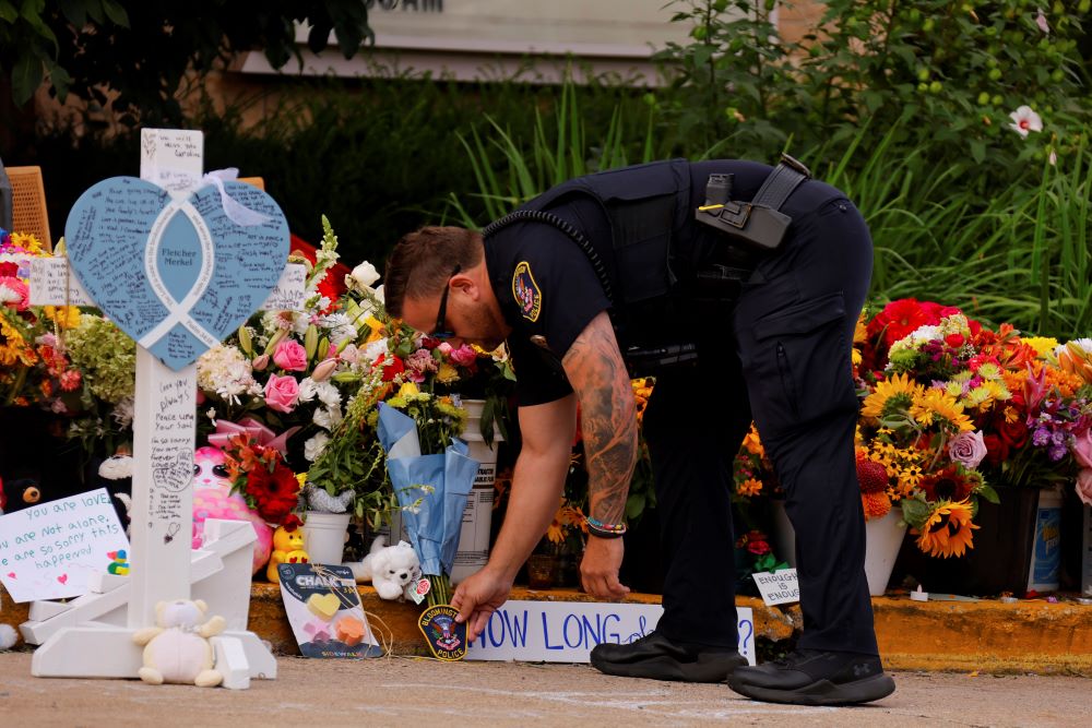 A police officer places a patch at a makeshift memorial at Annunciation Catholic Church.