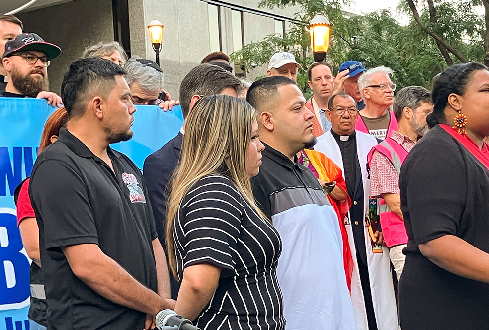 Kilmar Ábrego García, center, stands before a crowd of supporters at Baltimore's federal office building before his appointment with Immigration and Customs Enforcement on Aug. 25. Standing next to him is his wife, Jennifer Vasquez Sura. A short time later, Ábrego García was taken into custody. (Patricia Zapor)
