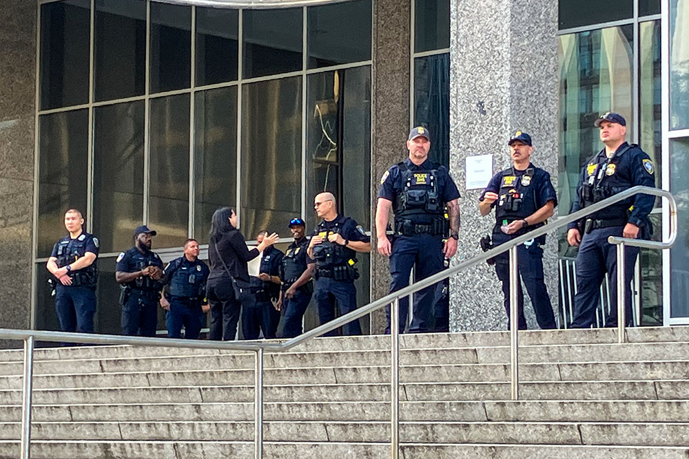 Police look out at people who gathered in front of the Baltimore federal building where Kilmar Ábrego García had an interview appointment with Immigration and Customs Enforcement and was taken into custody Aug. 25. (Patricia Zapor)