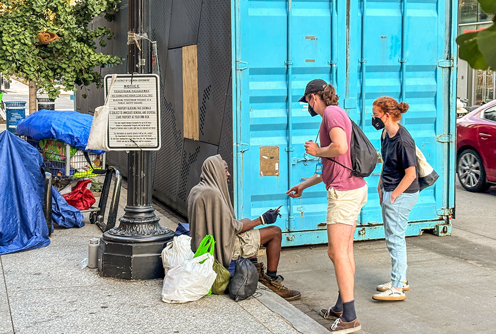 Volunteers offer information and a Metro card to a homeless man outside of the Martin Luther King Jr. Library in Washington, D.C., on Aug. 14, 2025. (NCR photo/James V. Grimaldi)