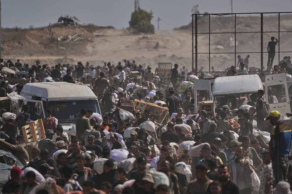 Palestinians carry humanitarian aid packages near a Gaza Humanitarian Foundation distribution center operated by the U.S.-backed organization, in Netzarim, central Gaza Strip, Aug. 4, 2025. (AP Photo/Abdel Kareem Hana)