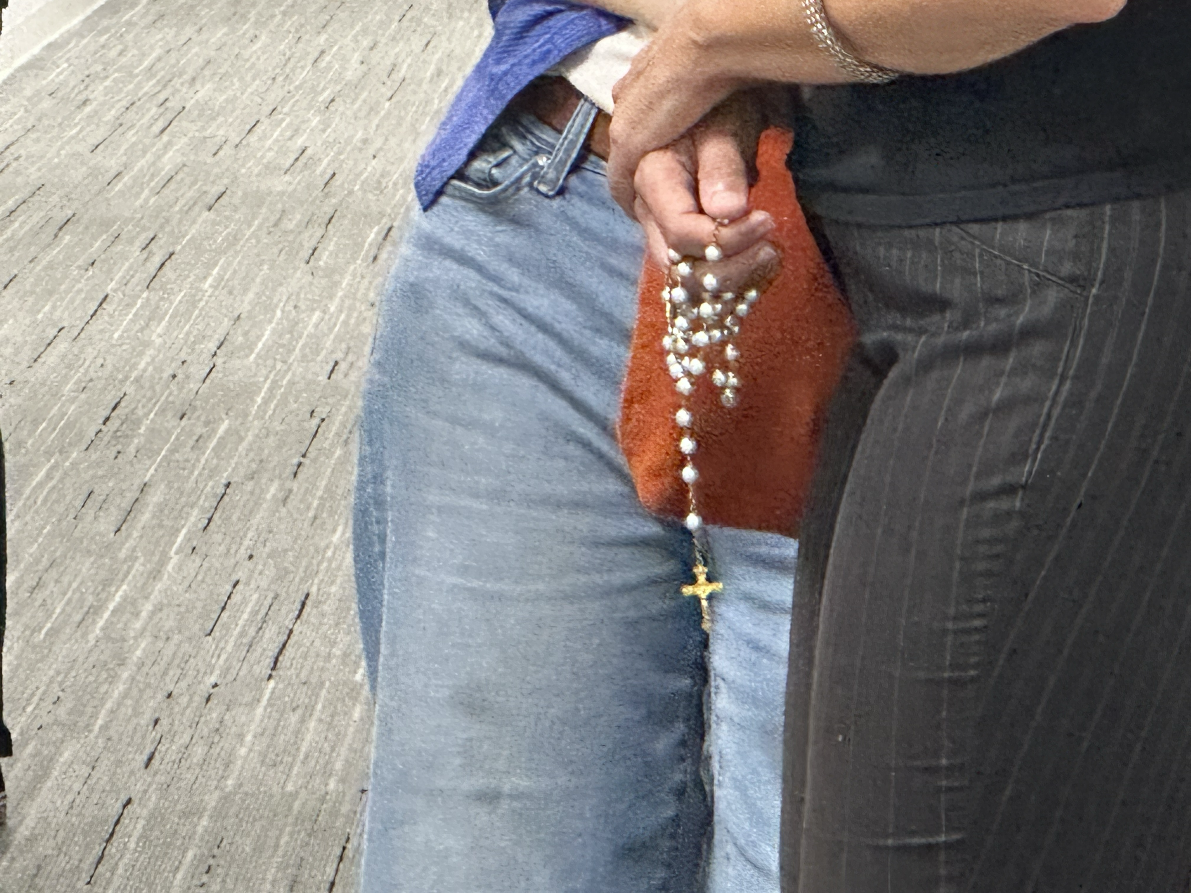 A member of the San Diego FAITH ministry holds a rosary as she waits outside immigration courtroom Aug. 6, 2025, the second day of ministry. (NCR photo/Chris Stone)