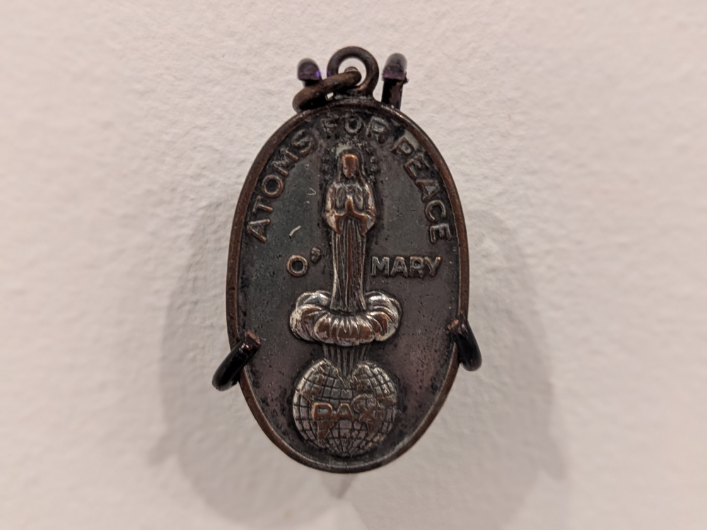 Resembling a Miraculous Medal, this pendant was most likely government propaganda aimed at American Catholics according to an explanatory sign at the "Fallout: Atoms for War & Peace" exhibit. (Mary Ann Cejka)
