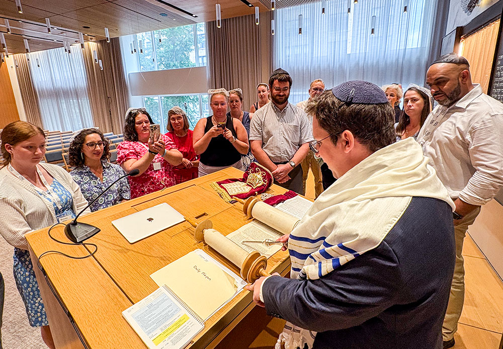 Rabbi Aiden Pink at Park Avenue Synagogue in Manhattan's Upper East Side shows a Torah to Catholic teachers who gathered in New York for the TOLI seminar, explaining to them how to read it, July 25, 2025. (NCR photo/Camillo Barone)
