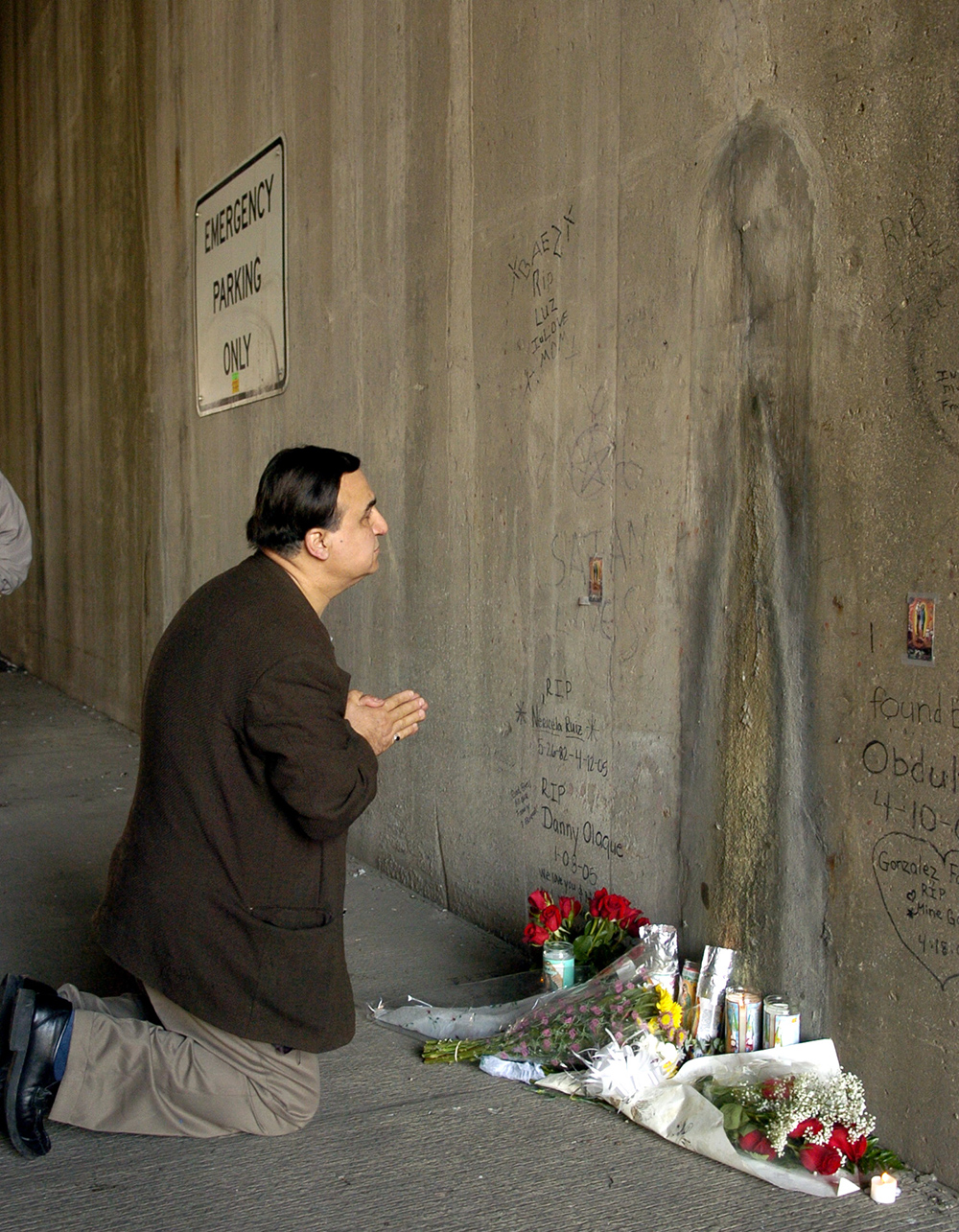 A Glenview man kneels in front of the image on the wall of the Kennedy Expressway underpass in April 2005. (Chicago Sun-Times file photo)