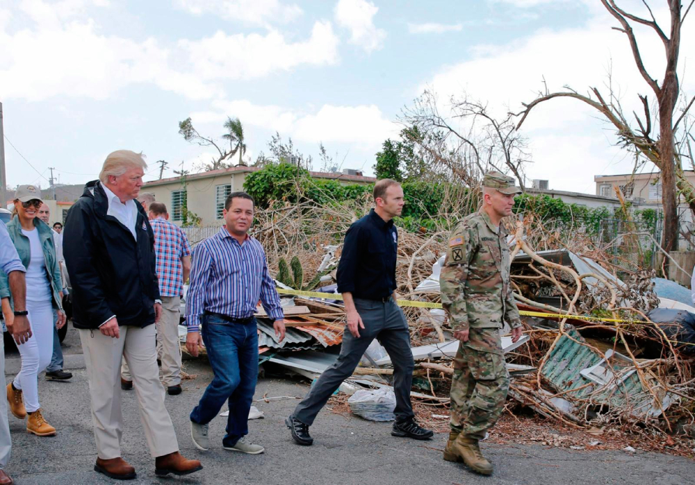 U.S. President Donald Trump walks past debris Oct. 3, 2017 during a tour with first lady Melania Trump, back left, Mayor Angel Perez Otero of Guaynabo, Puerto Rico, center left, in areas damaged by Hurricane Maria in Guaynabo.