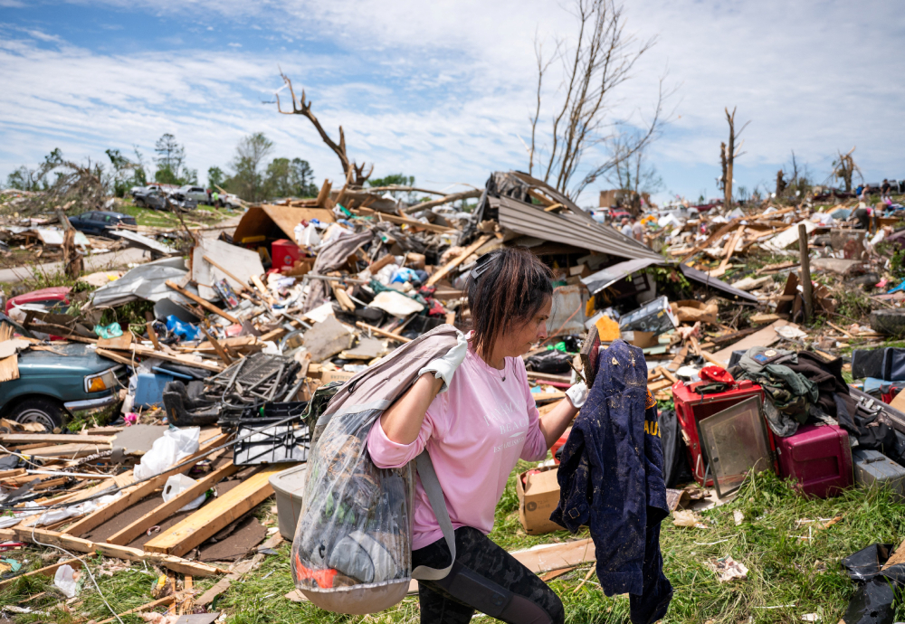 A woman carries belongings from a destroyed home in the Sunshine Hills neighborhood in London, Ky., May 18, 2025, after a series of tornadoes hit the area May 16. At least 27 people were killed by storm systems that swept across part of the U.S. Midwest and South. (OSV News / Reuters / Seth Herald)