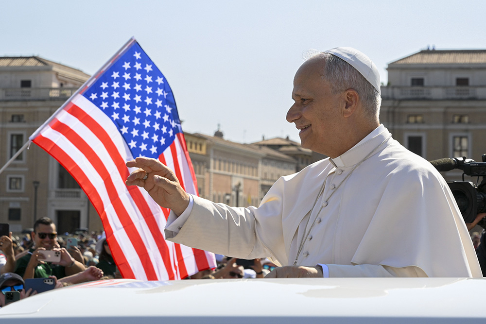 With a U.S. flag in the background, Pope Leo XIV waves to the crowd from the popemobile as he rides around St. Peter's Square at the Vatican before his weekly general audience Aug. 6, 2025. (CNS/Vatican Media)