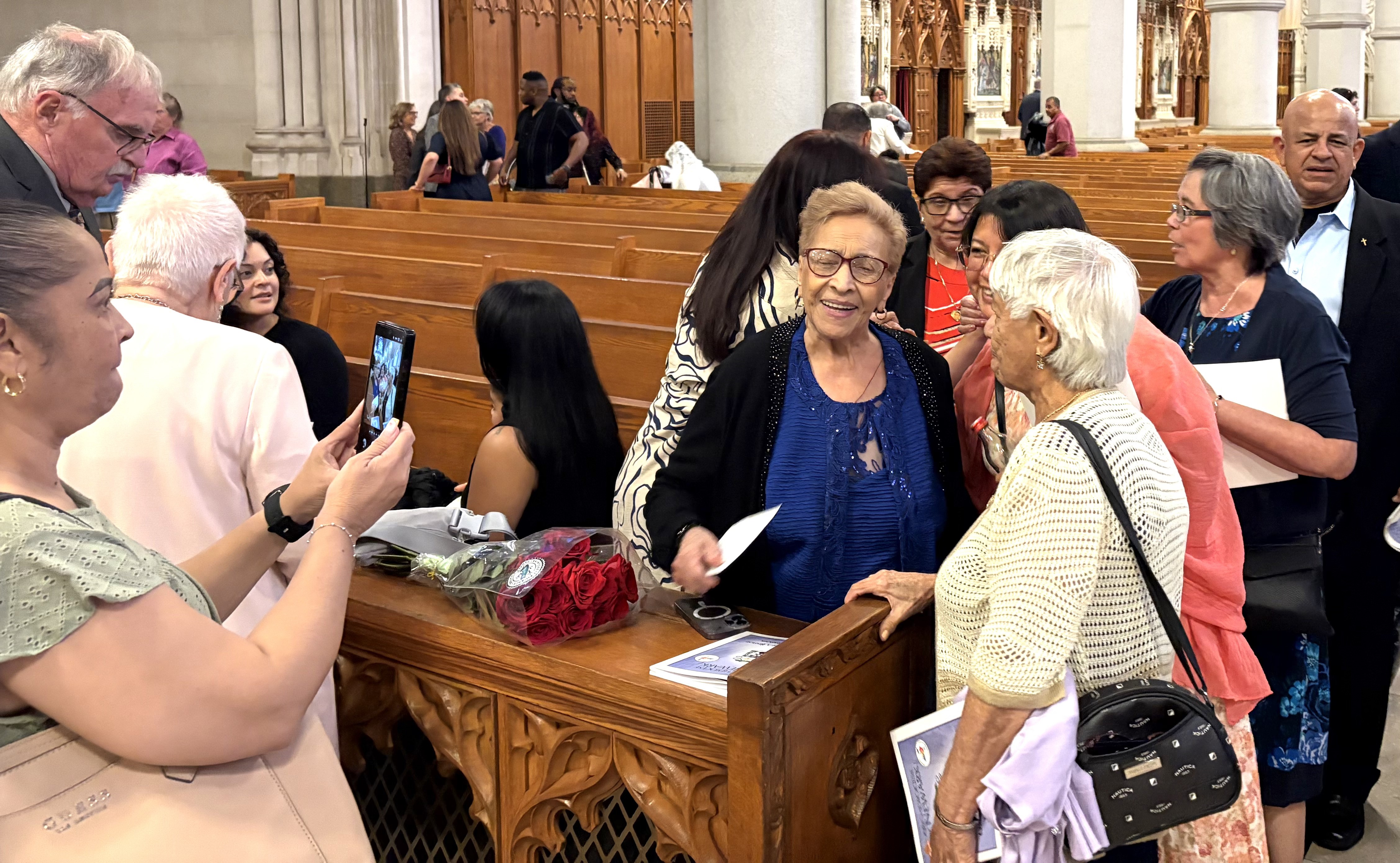 Friends, relatives and faithful from the Archdiocese of Newark greet Auxiliary Bishop Pedro Bismarck Chau's mother (center, in blue shirt) after Chau's consecration Mass, Sept. 8. (NCR photo/Camillo Barone)