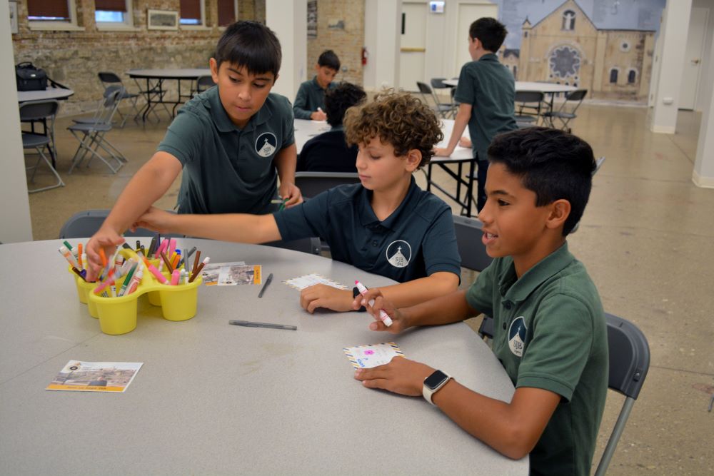 Fifth grade students at St. John Berchmans Elementary School fill out postcard invitations to the Sept. 7 Mass at their parish to commemorate Carlos Acuti's canonization in Rome.