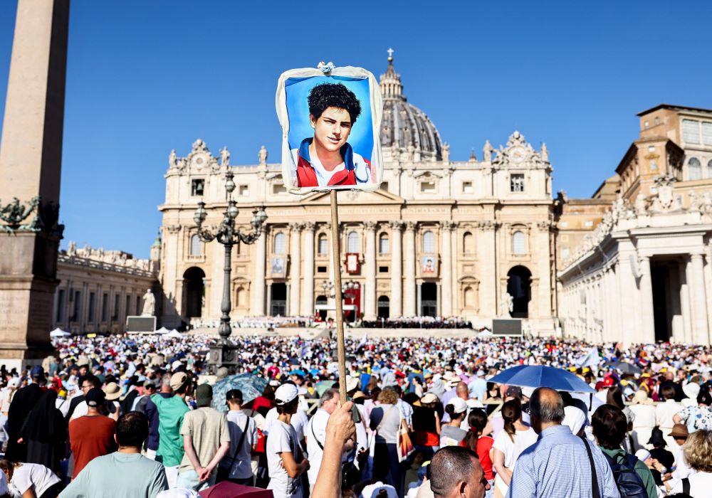 A person holds up a picture of Carlo Acutis as a crowd gathers at St. Peter's Square at the Vatican for the canonization ofAcutis and Pier Giorgio Frassati Sept. 7. (OSV News/Reuters/Matteo Minnella)