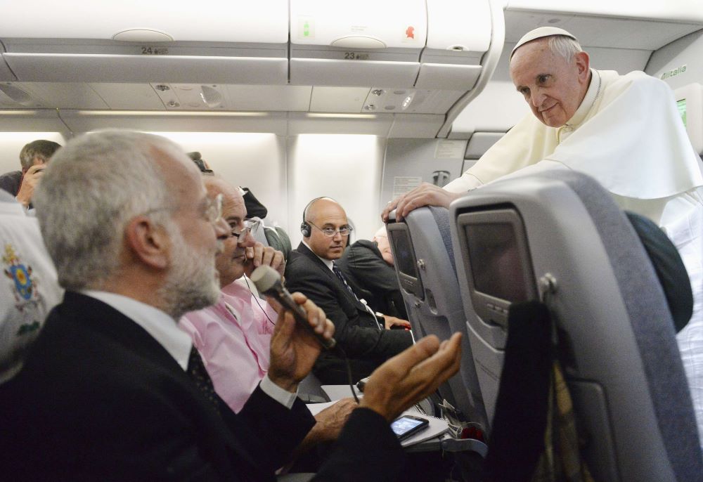 Pope Francis listens to a question from a journalist on his flight.