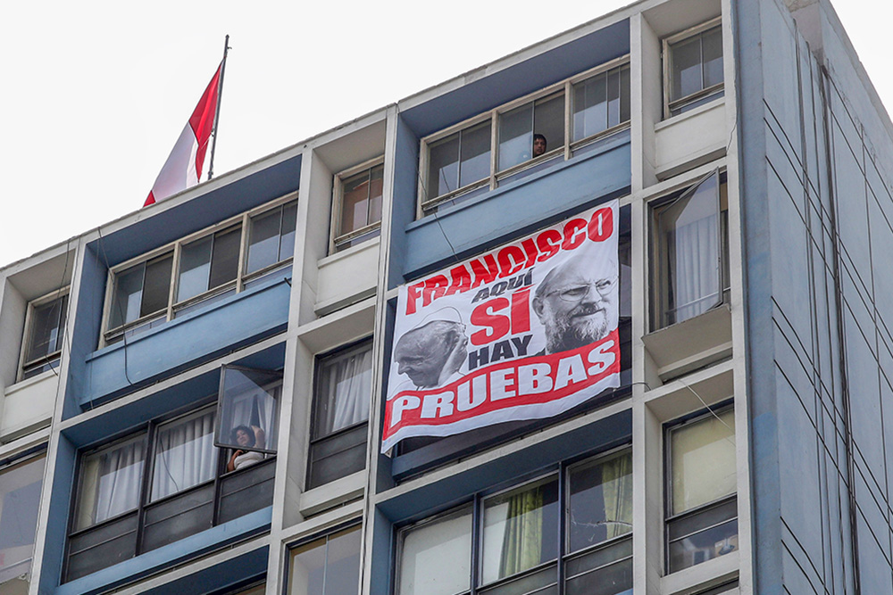A protest banner with images of Pope Francis and Luis Figari, the founder of Sodalitium Christianae Vitae, hangs from a building in Lima, Peru, Jan. 21, 2018, during Francis' visit to the country. The message reads in Spanish, "Francisco, here we do have proof." In an internal investigation published the previous year, Figari had been found responsible for the sexual abuse of minors and adults. (AP/Alessandra Tarantino)
