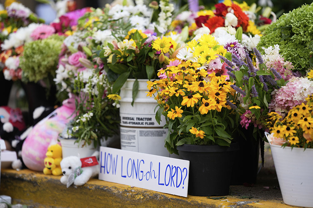 A sign stands amid flowers at a memorial at Annunciation Catholic Church after a school shooting Aug. 28, 2025, in Minneapolis. (AP/Abbie Parr)