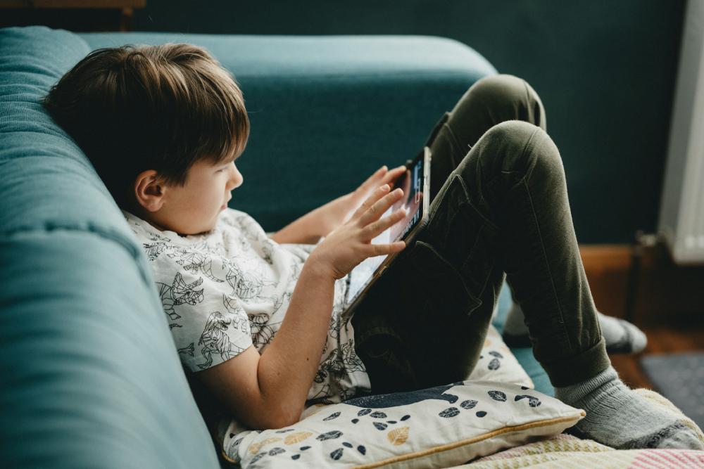Kid using a tablet on a sofa