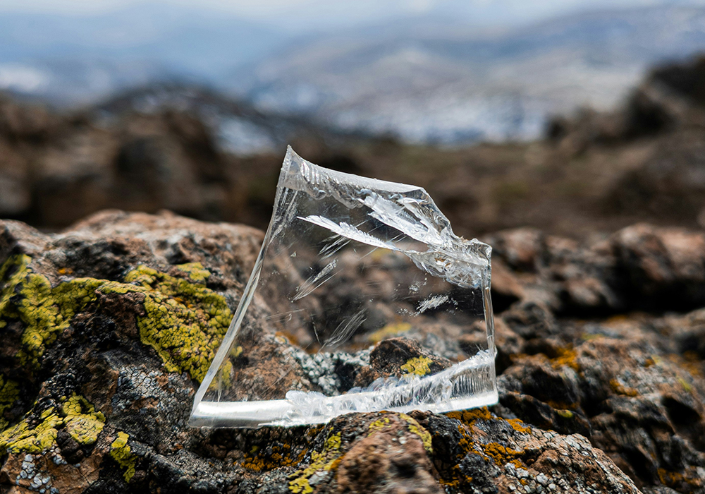 A piece of clear glass rests upon brown rock in this photo illustration. (Unsplash/Leutrim Fetahu)