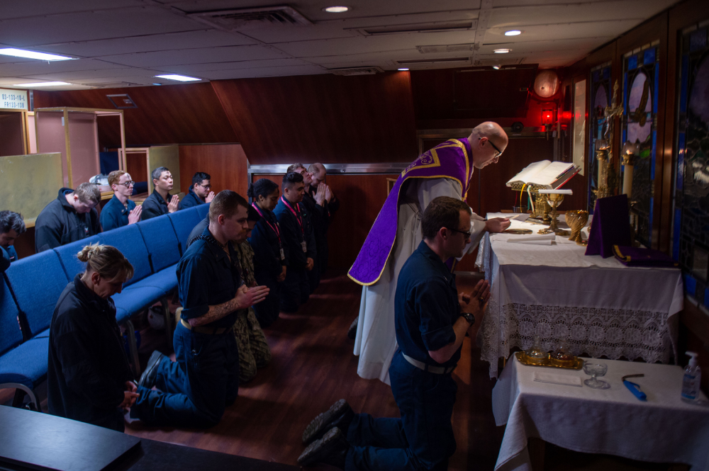 Lt. Jacob Meyer, center, a chaplain, reads from the Bible during a Catholic Ash Wednesday service in the chapel aboard the U.S. Navy's USS Ronald Reagan