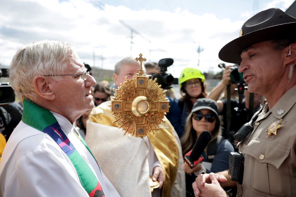 Jesuit Fr. Dan Hartnette speaks with an Illinois State Police officer as members of a Catholic group take part in a procession near the U.S. Immigration and Customs Enforcement Broadview facility in Chicago Oct. 11.