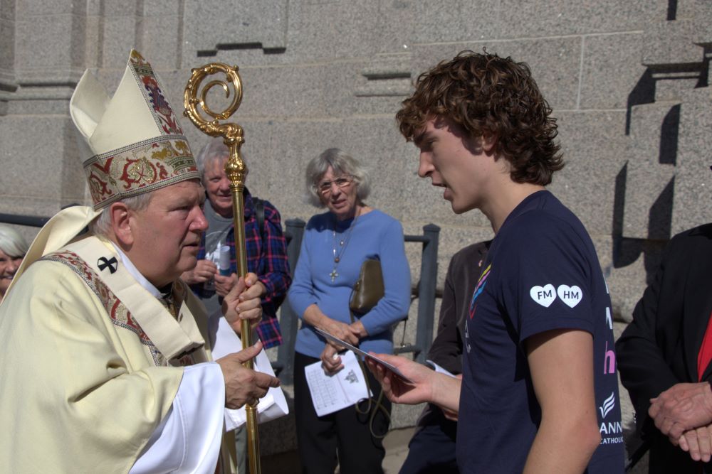 Archbishop Bernard Hebda accepts a letter Jimmy Kaiser wrote to Pope Leo XIV.