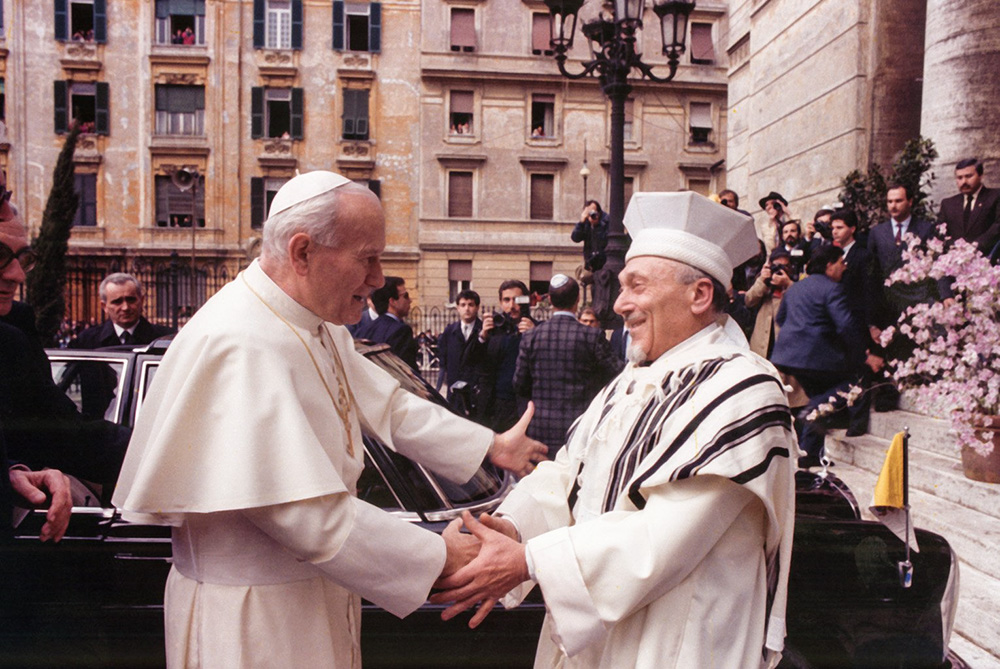 Pope John Paul II greets Rabbi Elio Toaff at Rome’s main synagogue April 13, 1986, in a meeting that marked the first time a pope had entered the Rome synagogue. The 1965 Vatican document Nostra Aetate, which turns 60 this year, paved the way for improved Catholic-Jewish relations. (CNS file/Arturo Mari)