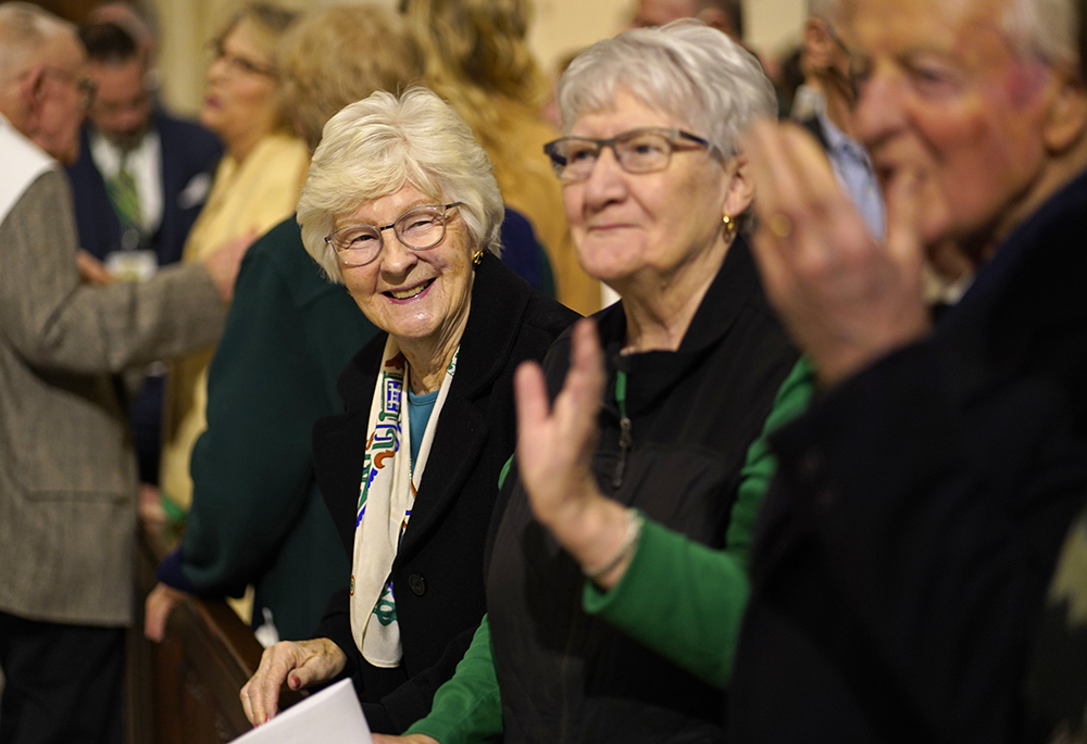 A woman smiles as she and other worshippers share the sign of peace during the St. Patrick's Day Mass at St. Patrick's Cathedral in New York City, March 17, 2023. (OSV News/Gregory A. Shemitz)