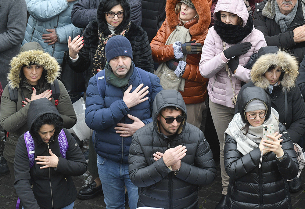 People gathered in St. Peter's Square at the Vatican for the recitation of the Angelus Jan. 7, 2024, the feast of the Baptism of the Lord, make the sign of the cross after Pope Francis asked them to do so in remembrance of having been baptized in the name of the Father, the Son and the Holy Spirit. (CNS/Vatican Media)
