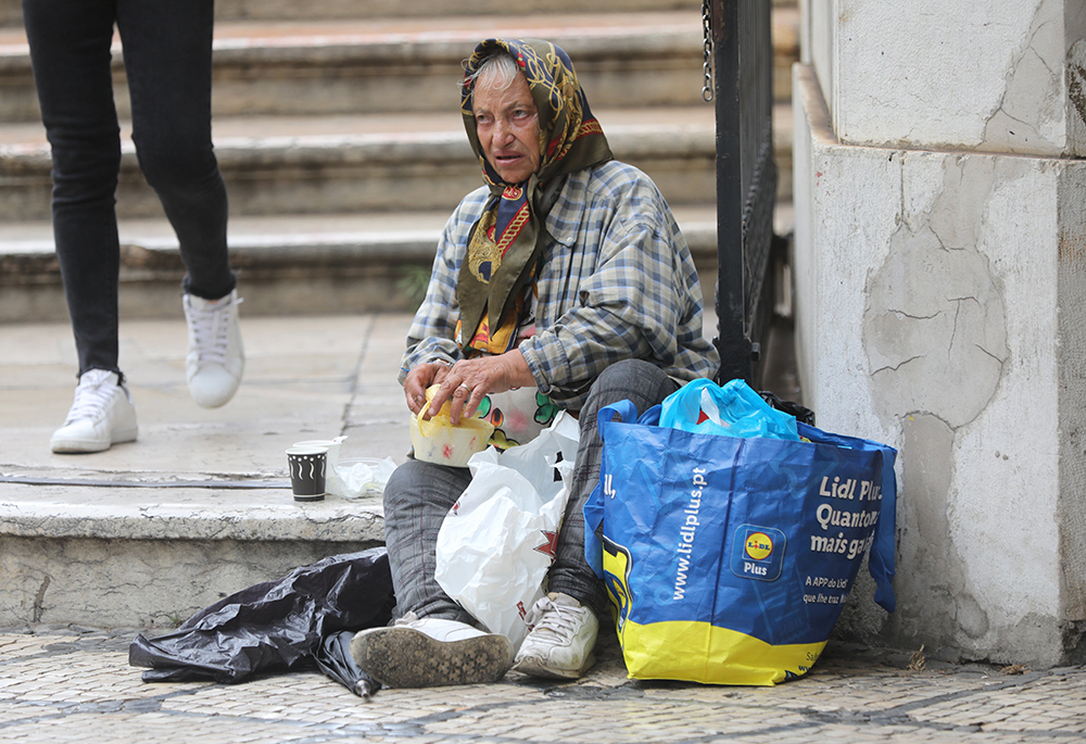 A pedestrian passes a homeless woman in Lisbon, Portugal, Aug 2, 2023. (OSV News/Bob Roller)