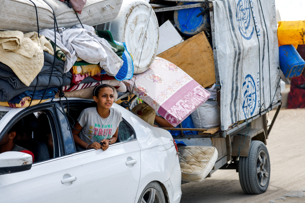 A Palestinian girl looks out from a window of a car carrying belongings, as she and other Palestinians who were displaced to the southern part of the Gaza Strip at Israel's order during the war make their way along a road, as they return to the north, amid a ceasefire between Israel and Hamas in Gaza City, Oct. 12, 2025. (OSV News/Reuters/Mahmoud Issa)
