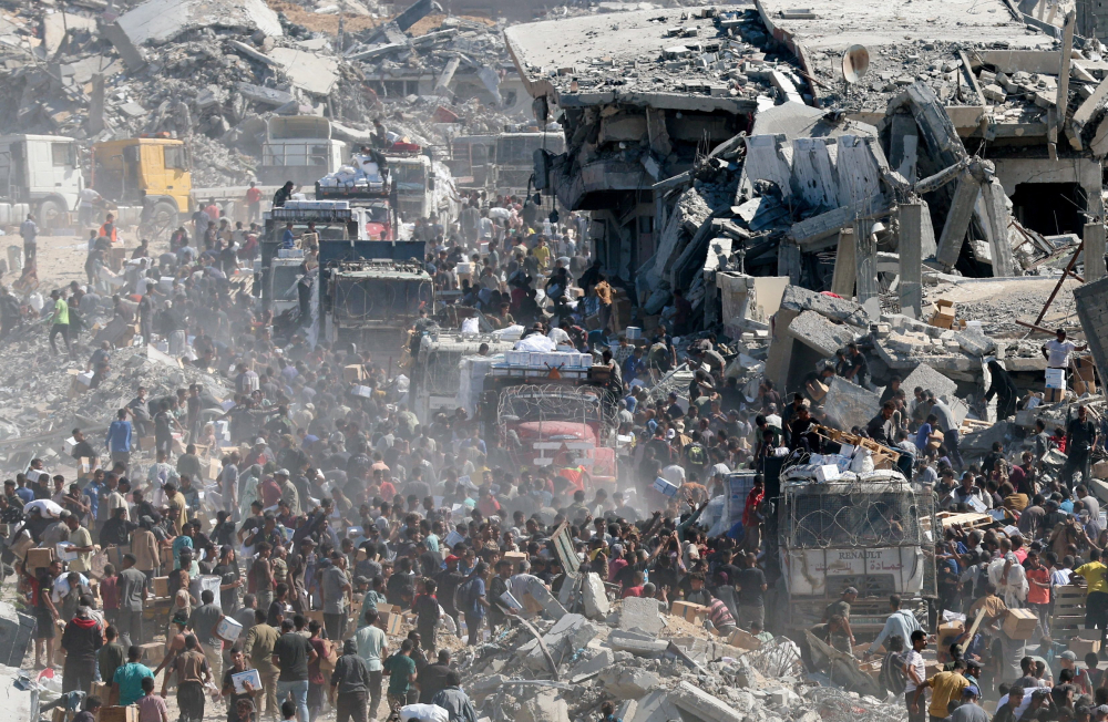 Palestinians collect aid supplies from trucks that entered the Gaza Strip, amid a ceasefire between Israel and Hamas in Gaza City, Oct. 12, 2025. (OSV News/Reuters/Ramadan Abed)
