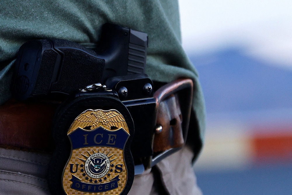 The badge and gun of a U.S. Immigration and Customs Enforcement agent is seen during an operation with migrants being transferred to a plane to be expelled under U.S. Title 42 from the United States to their home country by ICE and Border Patrol agents, at the airport in El Paso, Texas, May 10, 2023. (OSV News/Reuters/Jose Luis Gonzalez)