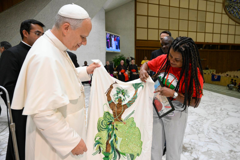 Pope Leo XIV holds a decorated piece of textile during a gathering of popular movements as part of their Jubilee in the Paul VI Audience Hall at the Vatican Oct. 23, 2025. (CNS/Vatican Media)