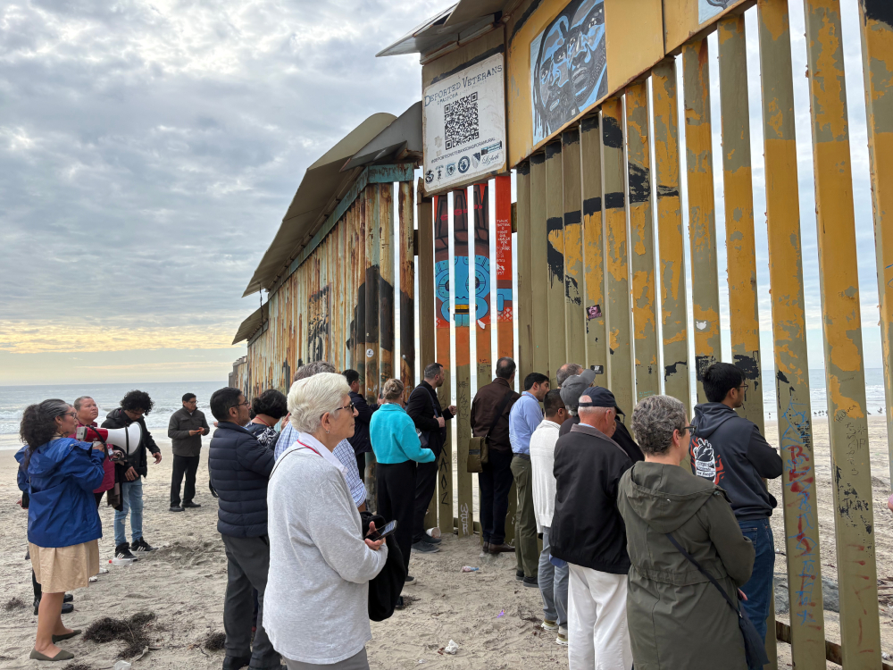 Attendees of the Colloquium on Migration and Theology reflect and pray at the border wall between Tijuana, Mexico, and San Diego, CA. (Luis Donaldo González)